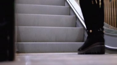 Alışveriş merkezinde yürüyen merdiven asansöründe yürüyen insan bacakları. Alışveriş merkezinde müşteriler yürüyen merdivende.