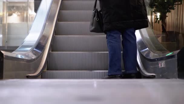 쇼핑몰의 에스컬레이터 엘리베이터를 타고 이동하는 사람들의 다리. 쇼핑 센터에서 에스컬레이터를 타고 있는 사람들 — 비디오