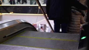 Alışveriş merkezinde yürüyen merdiven asansöründe yürüyen insan bacakları. Alışveriş merkezinde müşteriler yürüyen merdivende.