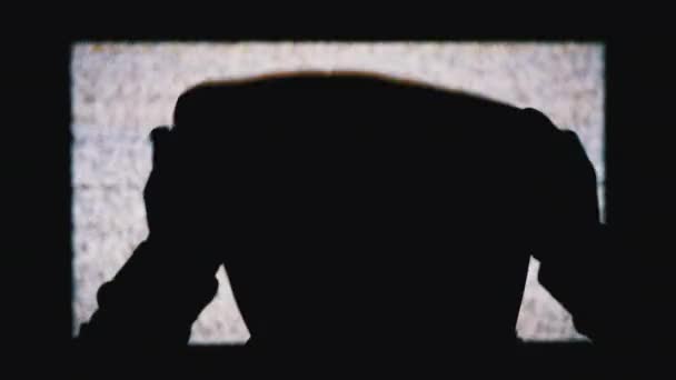 Silhouette des Mannes Kopf in Kapuze beobachtet weiße statische Geräusche und TV-Störungen. — Stockvideo
