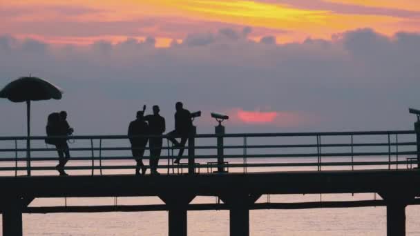 Silhouetten von Menschen auf der Seebrücke bei Sonnenuntergang — Stockvideo