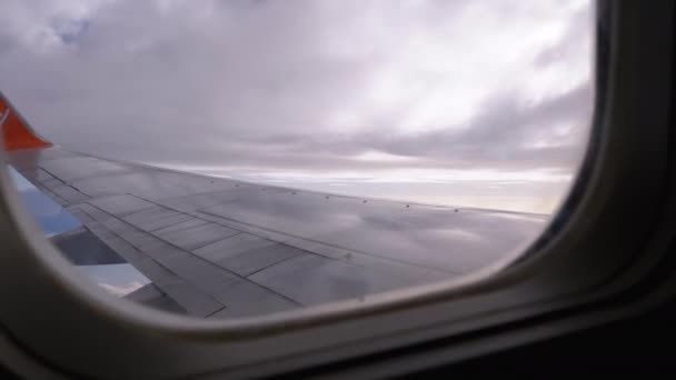 Vista da janela de um avião de passageiros na asa e nuvens no céu — Vídeo de Stock