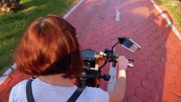Frau fährt mit Elektroroller auf rotem Radweg mit Palmen in der Kurstadt