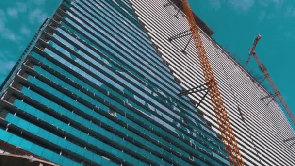 푸른 하늘 과맞닿은 공사장에 크레인 이 새로운 초고층 건물을 짓고 있습니다. 건축 공사. — 비디오