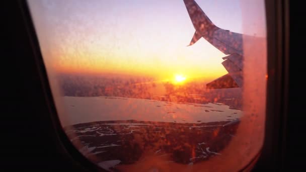 Zicht vanuit het vliegtuigvenster op de vleugel tijdens zonsondergang — Stockvideo