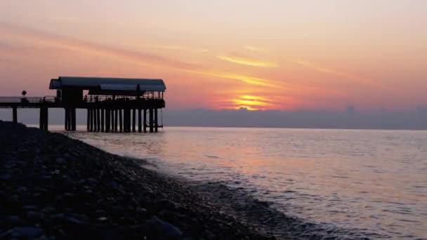 Panorama de la puesta de sol sobre el mar junto a la silueta del muelle . — Vídeos de Stock