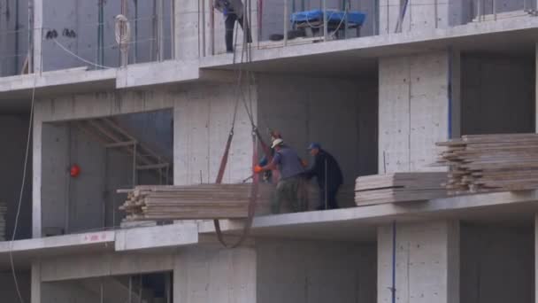 Constructores en un sitio de construcción. Grúa en un sitio de construcción levanta una carga. Construcción de edificios . — Vídeos de Stock