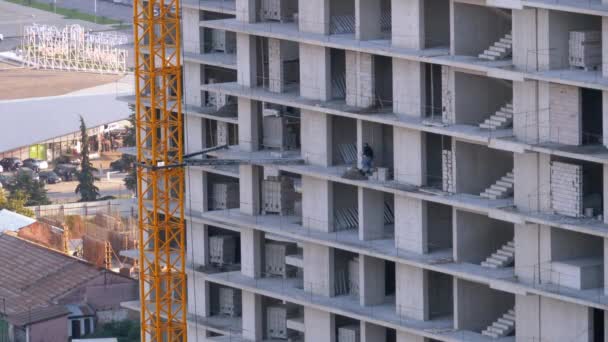 Sitio de construcción con constructor y grúa. Un trabajador en una obra de construcción . — Vídeos de Stock