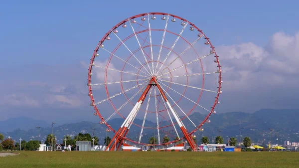 Güneşli bir günde, Palmiye ağaçlarının yanında bulutlar varken, Mavi Gökyüzüne karşı dönme dolap.