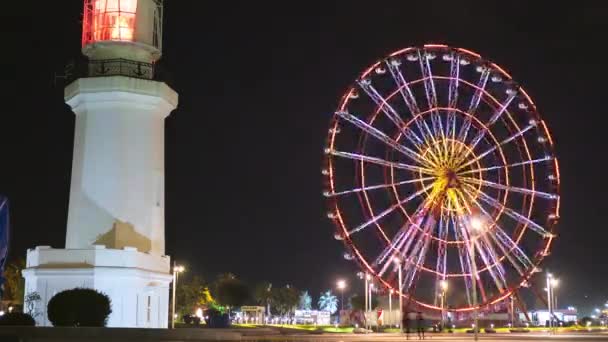 Diabelski młyn w pobliżu latarni obraca się nocą na nabrzeżu Batumi — Wideo stockowe