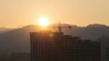 Sunrise over a Tower Crane on Construction Site with a Skyscraper in the City. Timelapse.