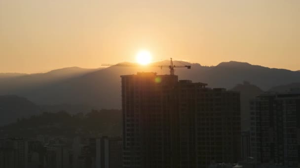 Lever de soleil sur une grue à tour sur le chantier avec un gratte-ciel dans la ville. Temps écoulé . — Video