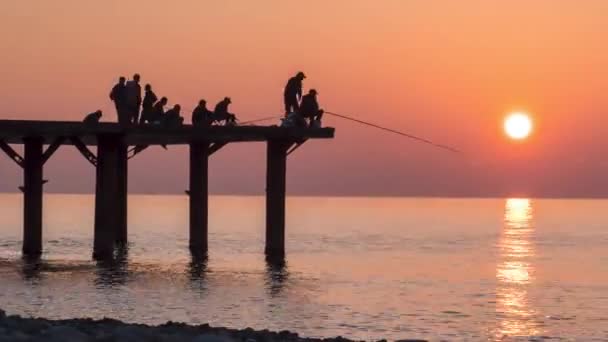 Silhouette di pescatori con canne da pesca al tramonto sul molo. Rallentatore . — Video Stock