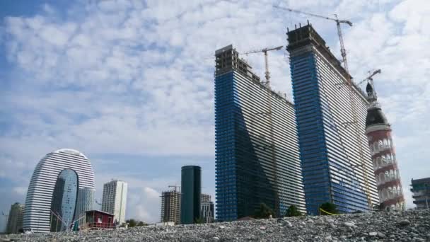 Construcción de un rascacielos moderno utilizando grúas torre. Timelapse. Nubes móviles en el cielo azul — Vídeo de stock