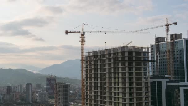 Будівництво. Тімелапс. Tower Crane на будівельному майданчику піднімає навантаження на висотний будинок. — стокове відео