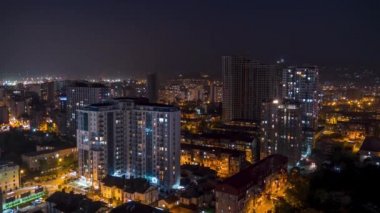 Şehirde geceleri değişen pencere ışıklarıyla çok katlı binalar. Zaman Uygulaması