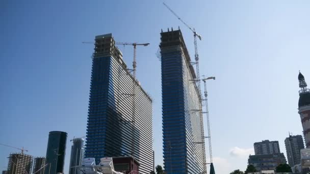 Timelapse de la construcción de un rascacielos moderno utilizando grúas torre sobre un fondo de cielo azul — Vídeos de Stock