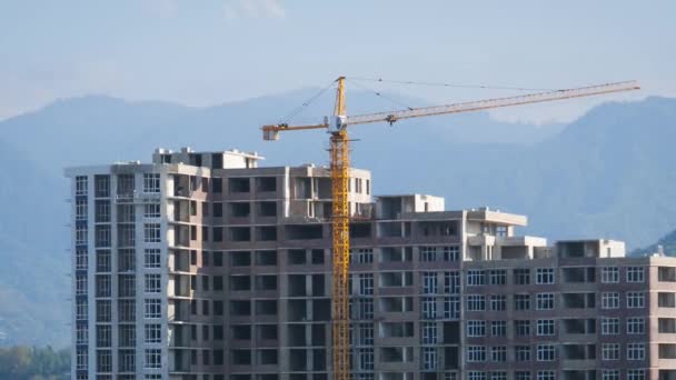 O guindaste da torre em um canteiro de obras levanta uma carga no edifício alto. Prazo de validade — Vídeo de Stock