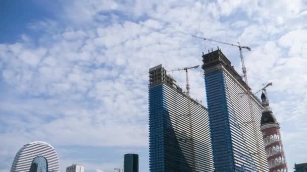 Construcción de un rascacielos moderno utilizando grúas torre. Timelapse. Nubes móviles en el cielo azul — Vídeos de Stock