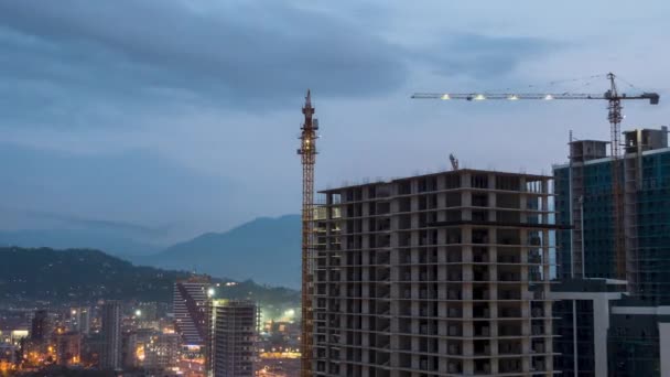 Construcción de edificios de día a noche. Timelapse. Grúa de torre con iluminación en un sitio de construcción — Vídeo de stock