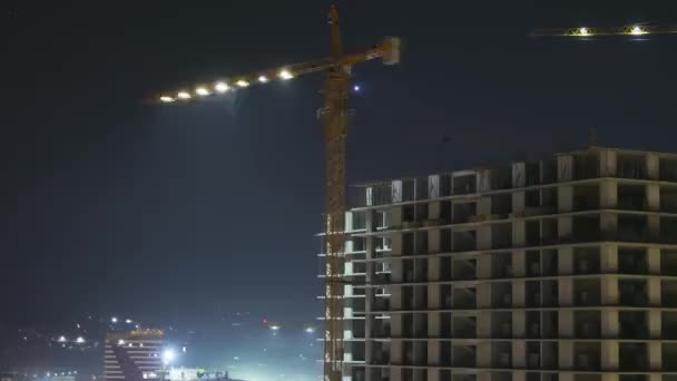 Bouwbedrijf 's nachts. Tijdsverloop. Tower Crane op een bouwplaats met verlichting — Stockvideo