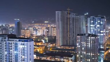 Şehirde geceleri değişen pencere ışıklarıyla çok katlı binalar. Zaman Uygulaması