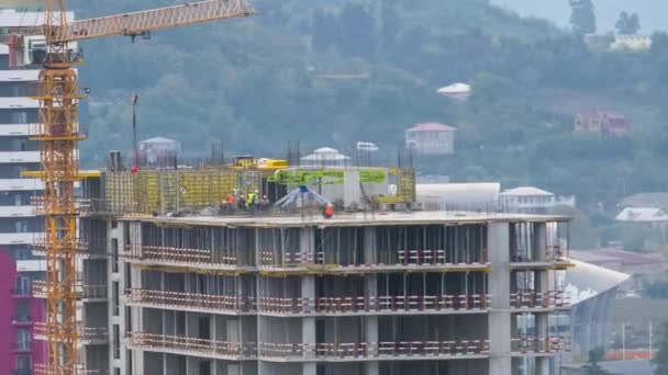 Hochbau. Zeitraffer. Turmdrehkran auf einer Baustelle hebt eine Last. Bauarbeiter arbeiten. — Stockvideo