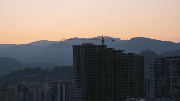 Salida del sol sobre una grúa torre en el sitio de construcción con un rascacielos en la ciudad. Cronograma . — Vídeo de stock