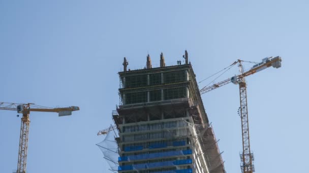 Tower Crane op een bouwplaats tilt een lading op bij High-rise Building. Tijdsverloop. — Stockvideo