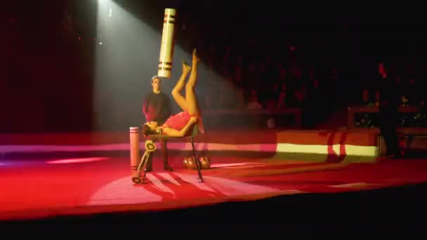 Vrouw liggend draait de cilinder met haar benen op het circus podium — Stockvideo