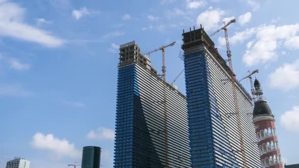 Construção de um arranha-céus modernos usando guindastes de torre. Timelapse. Nuvens móveis no céu azul — Vídeo de Stock