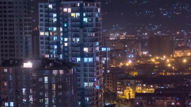 Edificios de varios pisos con iluminación cambiante de ventanas por la noche en la ciudad. Cronograma — Vídeo de stock