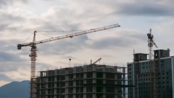 Time Lapse of Tower Cranes on a Construction Site Lift a Load at High-rise Building. — Stock video