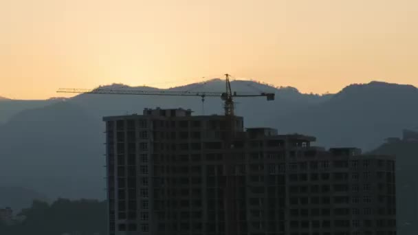 Salida del sol sobre una grúa torre en el sitio de construcción con un rascacielos en la ciudad. Cronograma . — Vídeo de stock