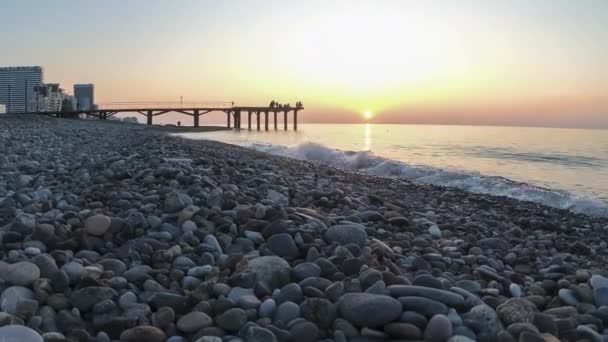 Panorama des Sonnenuntergangs über dem Meer. Steinstrand mit Meereswellen. — Stockvideo