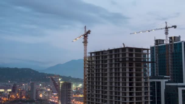 Costruzione di edifici dal giorno alla notte. Timelapse. Gru a torre con illuminazione in cantiere — Video Stock