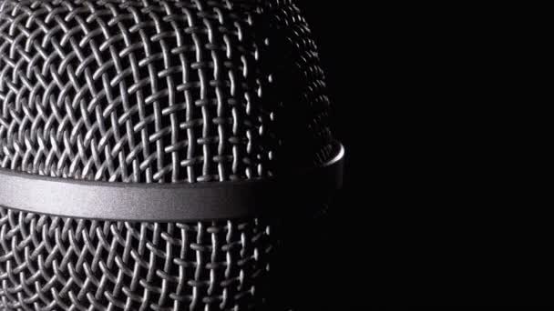 Das Mikrofon dreht sich auf schwarzem Hintergrund. dynamisches Mikrofonnetz dreht sich aus nächster Nähe — Stockvideo