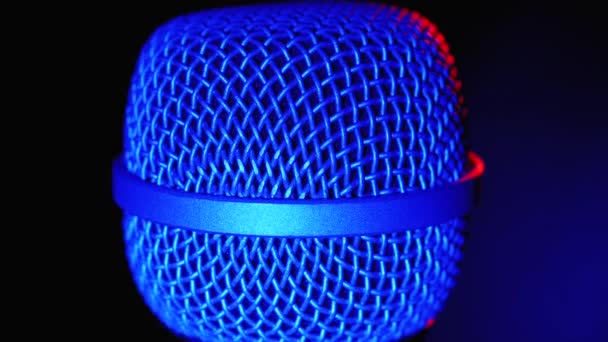 Mikrofon obraca się z niebieskim i czerwonym podświetleniem. Dynamiczna siatka mikrofonu obraca się w zbliżeniu — Wideo stockowe