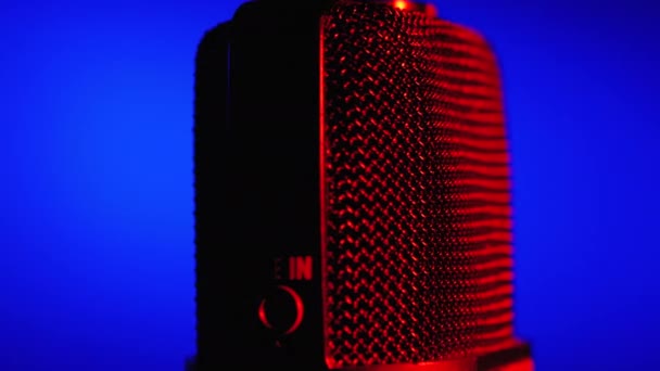 Microfone condensador gira com luz de fundo azul e vermelha. Gravador de áudio profissional Close-up — Vídeo de Stock