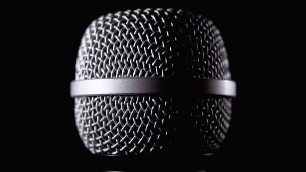O microfone gira em um fundo preto. Giros dinâmicos da grade do microfone Close-up — Vídeo de Stock