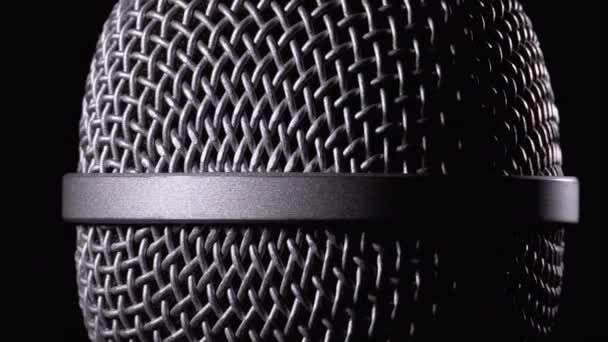 Das Mikrofon dreht sich auf schwarzem Hintergrund. dynamisches Mikrofonnetz dreht sich aus nächster Nähe — Stockvideo