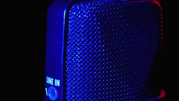 Micrófono de condensador gira con luz de fondo azul y rojo. Grabadora de audio profesional Primer plano — Vídeo de stock