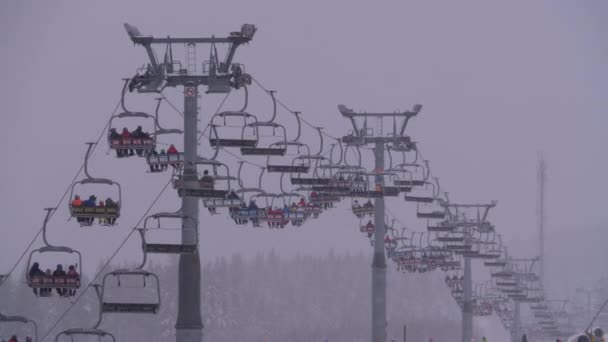 Impianti di risalita sulla stazione sciistica. Sciatori Salire su una sedia da sci Ascensore fino alla pista da sci con neve cadente — Video Stock