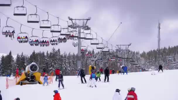 Катание на лыжах и сноубордистах по снежному склону на горнолыжном курорте в солнечный день — стоковое видео