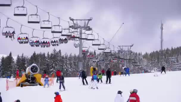 Skidåkare och snowboardåkare Rider på en snöig backe på en skidort på soliga dagen — Stockvideo