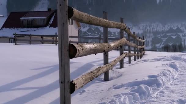 Winter Rural Scene with Old Abandoned Wooden Fence and Snowy Wooden House and Mountains — Stockvideo