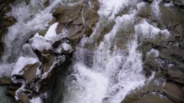 Rapid Flow of Water from a Mountain Creek and Stone Rapids with Snow in Winter. Cascade. Mouvement lent 