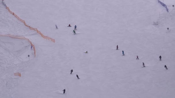 Skiërs en snowboarders rijden op een besneeuwde piste op een skigebied in Sunny Day — Stockvideo