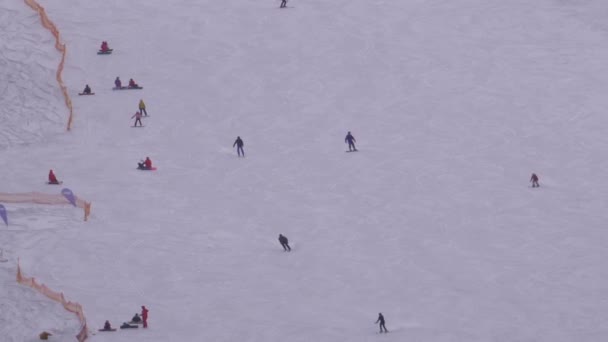 Skiërs en snowboarders rijden op een besneeuwde piste op een skigebied in Sunny Day — Stockvideo