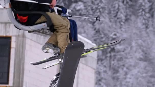 Esquiadores num elevador de esqui. Pernas com esquis e botas de esqui em pano de fundo de pinhos nevados na floresta . — Vídeo de Stock